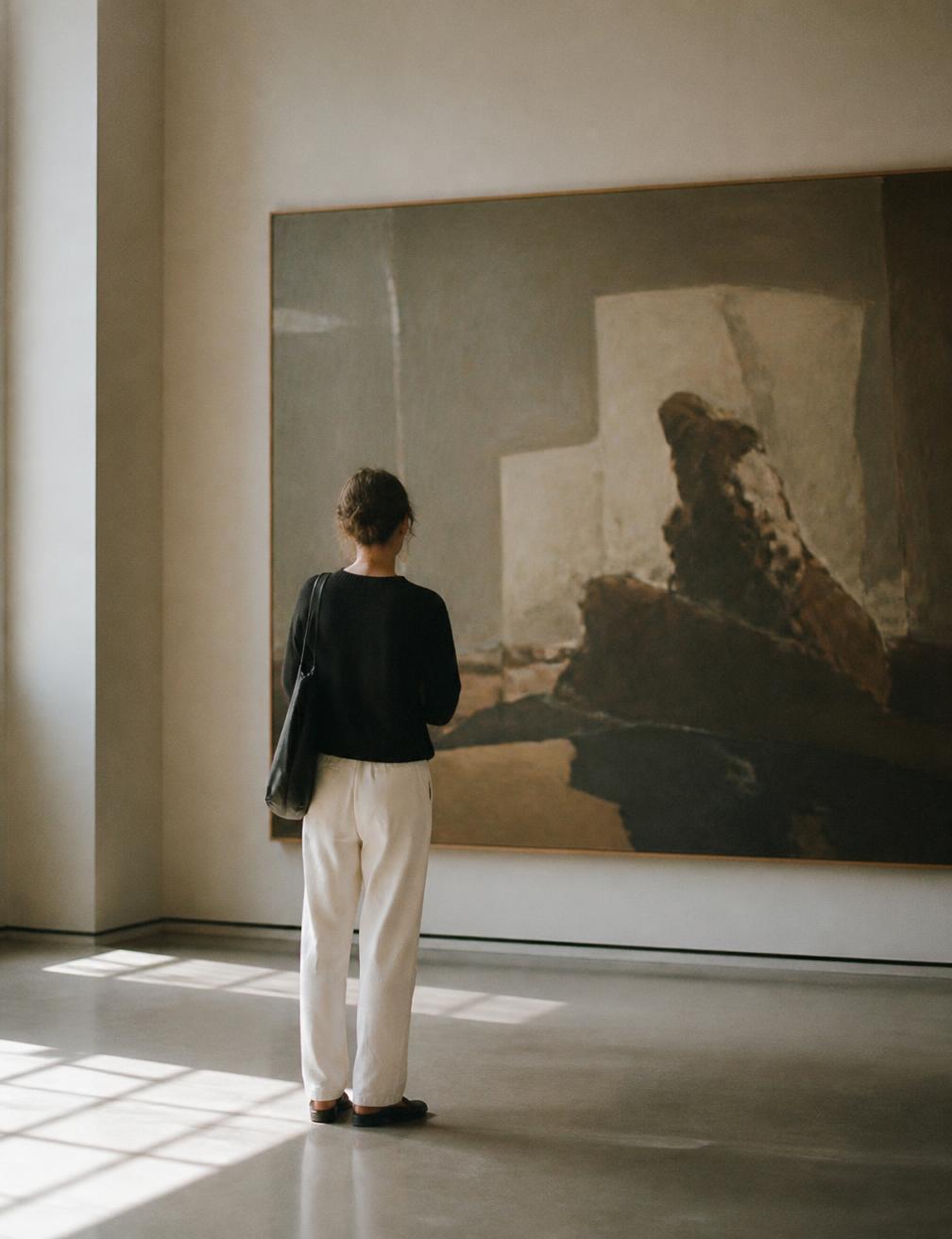 A visitor pausing in front of artwork in a quiet gallery